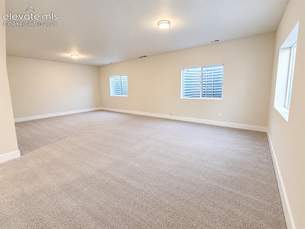 Image 20 of 26: Expansive room featuring neutral-toned carpeting, light beige walls, and mu