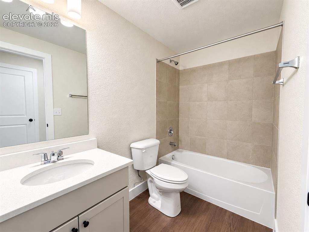 Image 23 of 26: Bathroom with a white vanity, integrated sink, chrome faucet, and rectangul