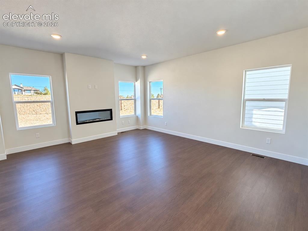 Image 4 of 26: Expansive room featuring wood-finish flooring, recessed lighting, multiple