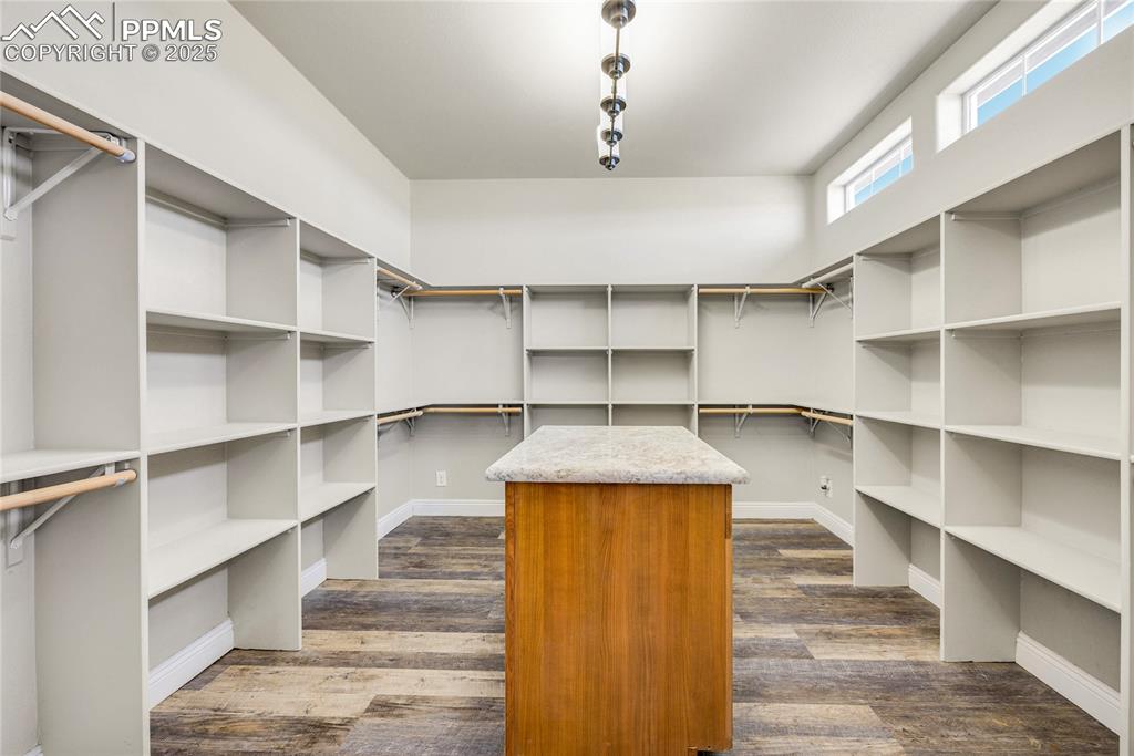 Image 15 of 50: Walk in closet with dark wood finished floors