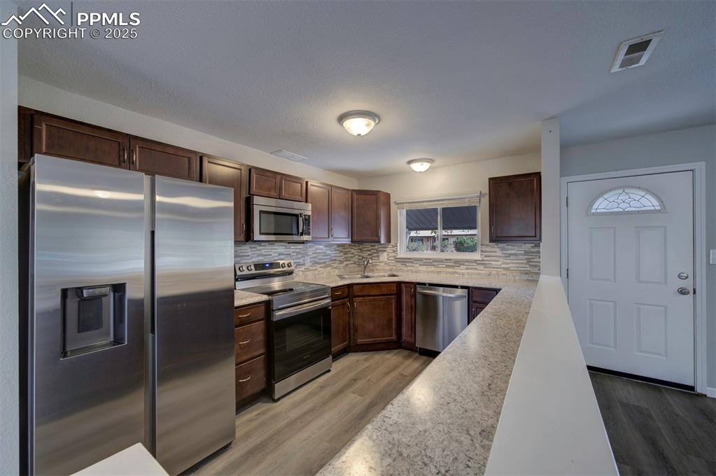 Image 10 of 43: Kitchen with stainless steel appliances, light wood finished floors, tastef