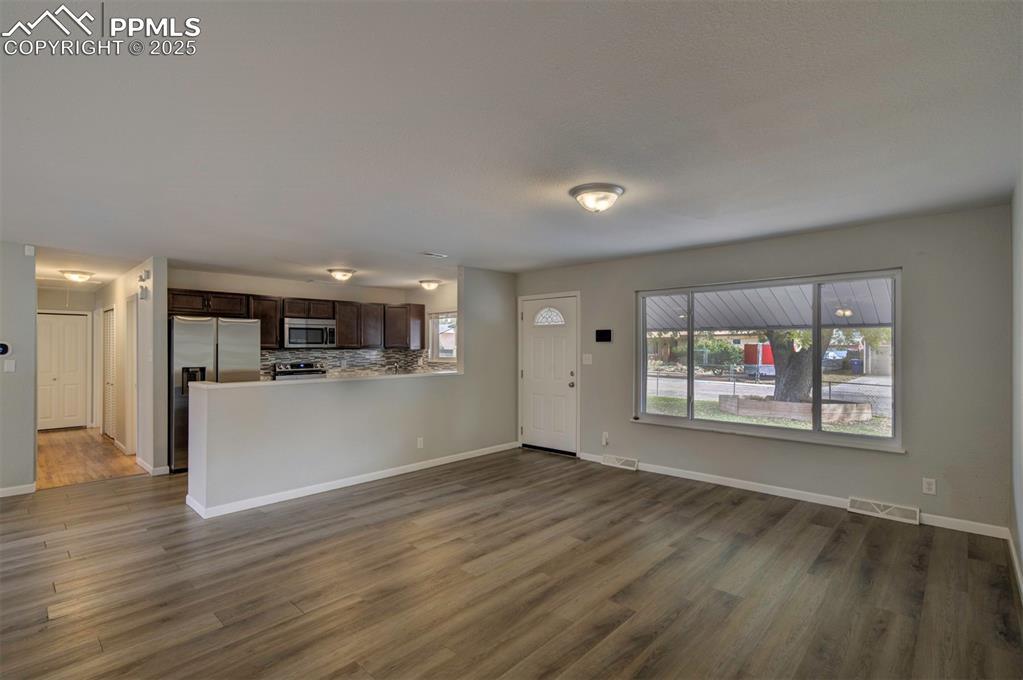 Image 11 of 43: Unfurnished living room featuring baseboards and wood type finished floors