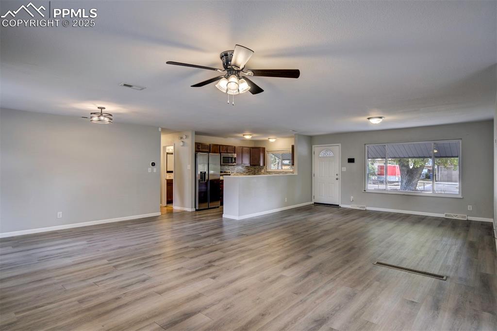 Image 13 of 43: Unfurnished living room featuring wood-style floors and ceiling fan