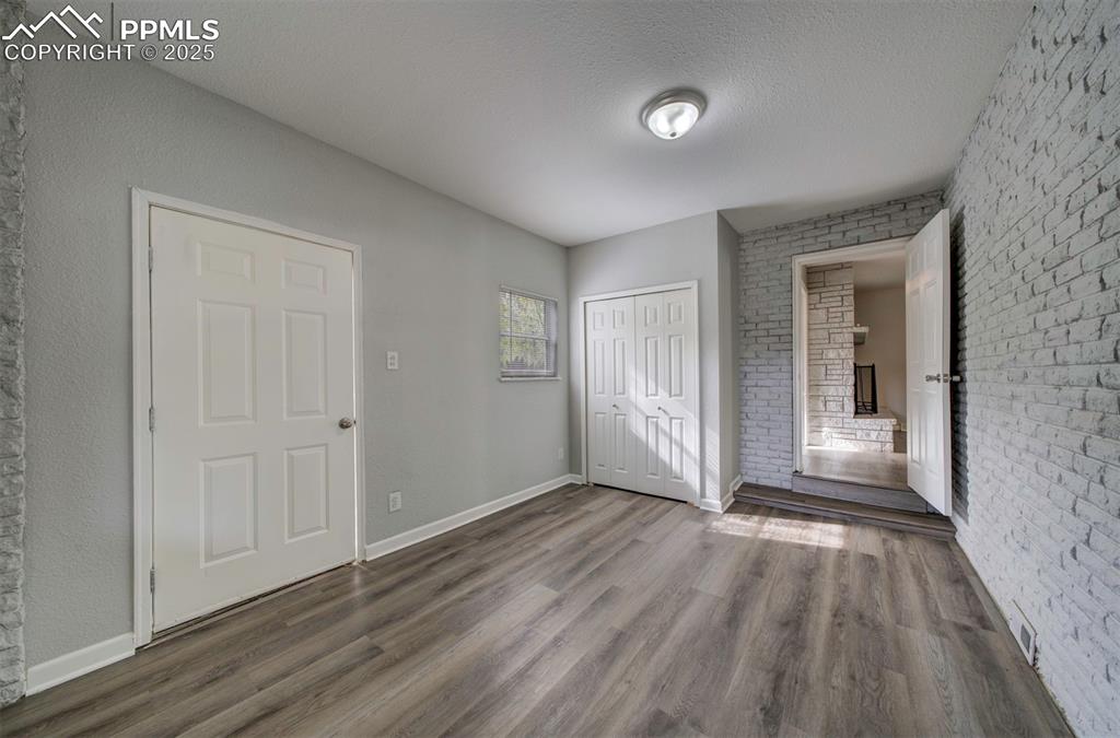 Image 18 of 43: Unfurnished bedroom with brick wall, wood-style floors, closet, and walkout