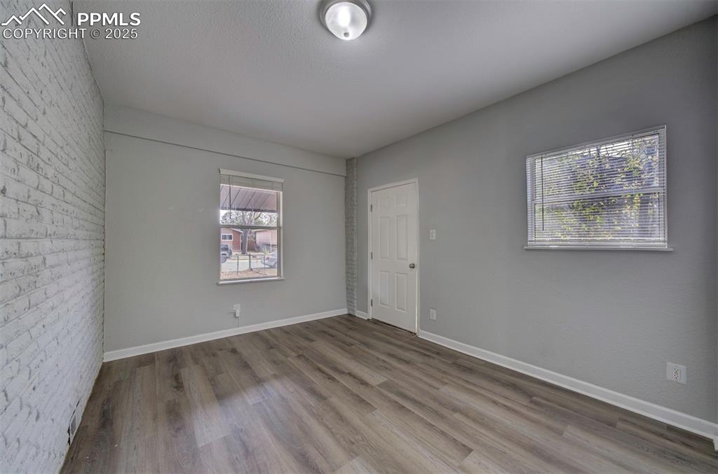 Image 20 of 43: Unfurnished room featuring brick wall and wood style floors