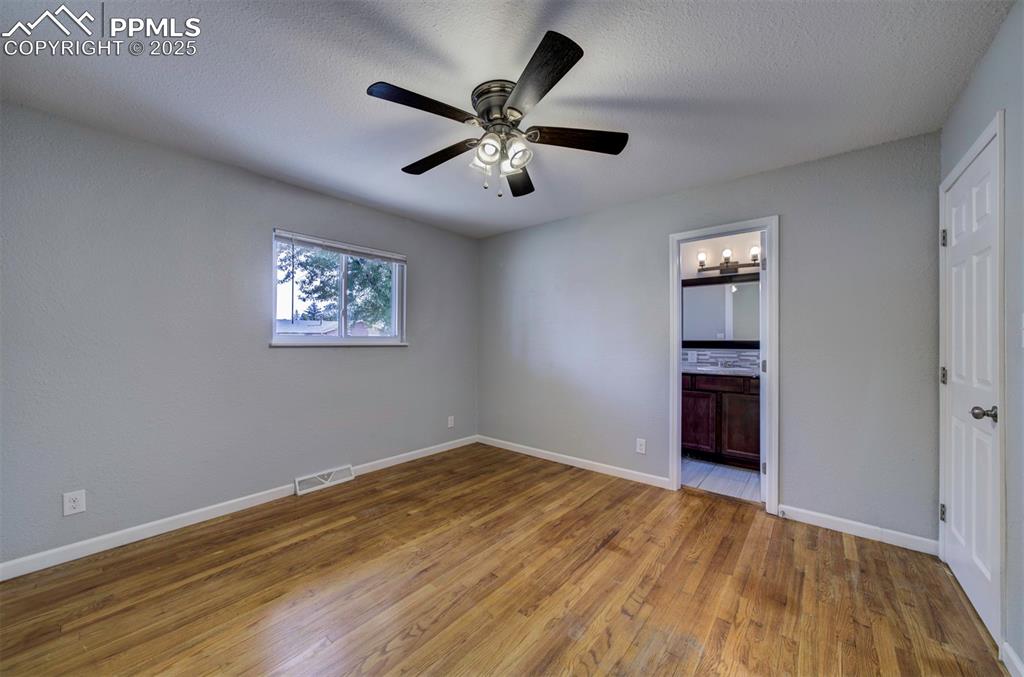 Image 32 of 43: Unfurnished bedroom featuring wood floors, ceiling fan, closet, and adjoini