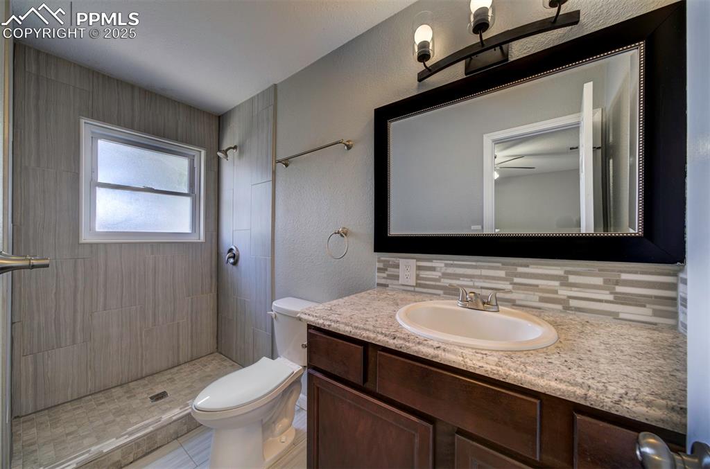 Image 33 of 43: Bathroom featuring a tiled shower, vanity, decorative backsplash