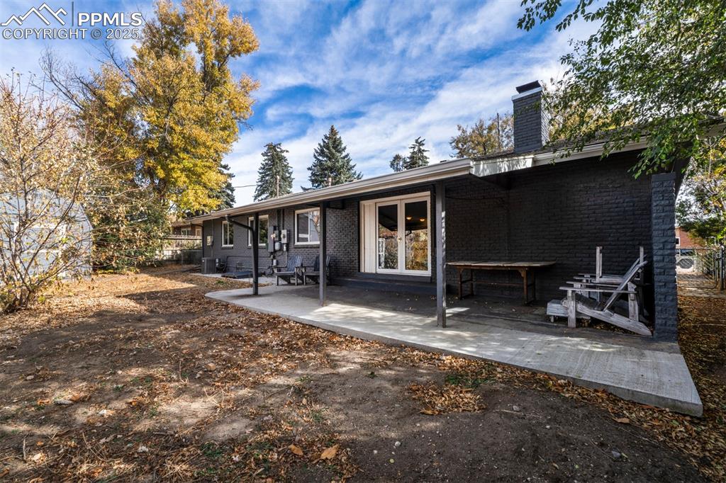 Image 37 of 43: Back of property with french doors, brick siding, a patio, and a chimney