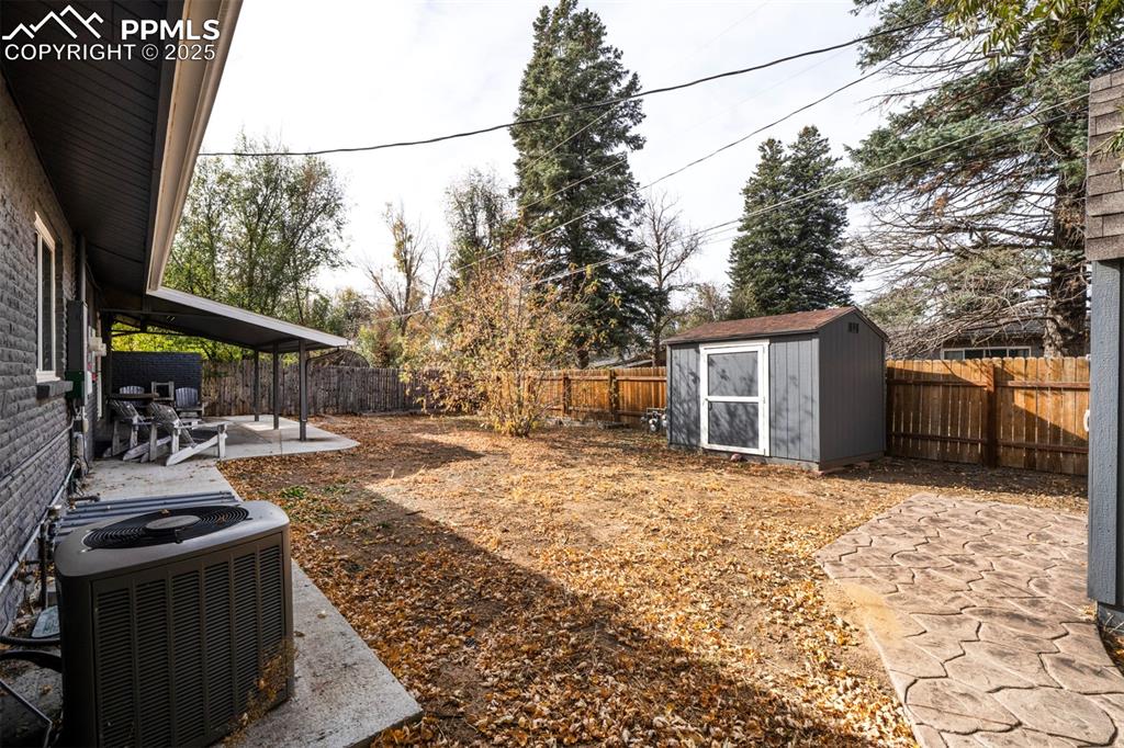 Image 39 of 43: Fenced backyard with a covered patio area and a 2 sheds