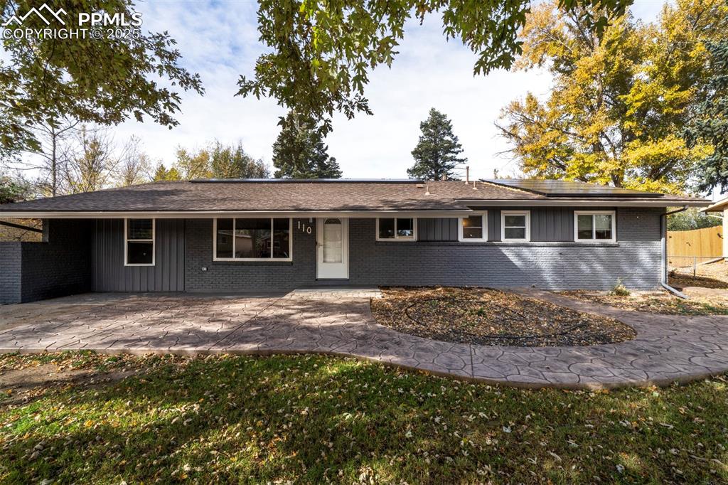 Image 4 of 43: Ranch-style home with brick siding and concrete patio with path to backyard