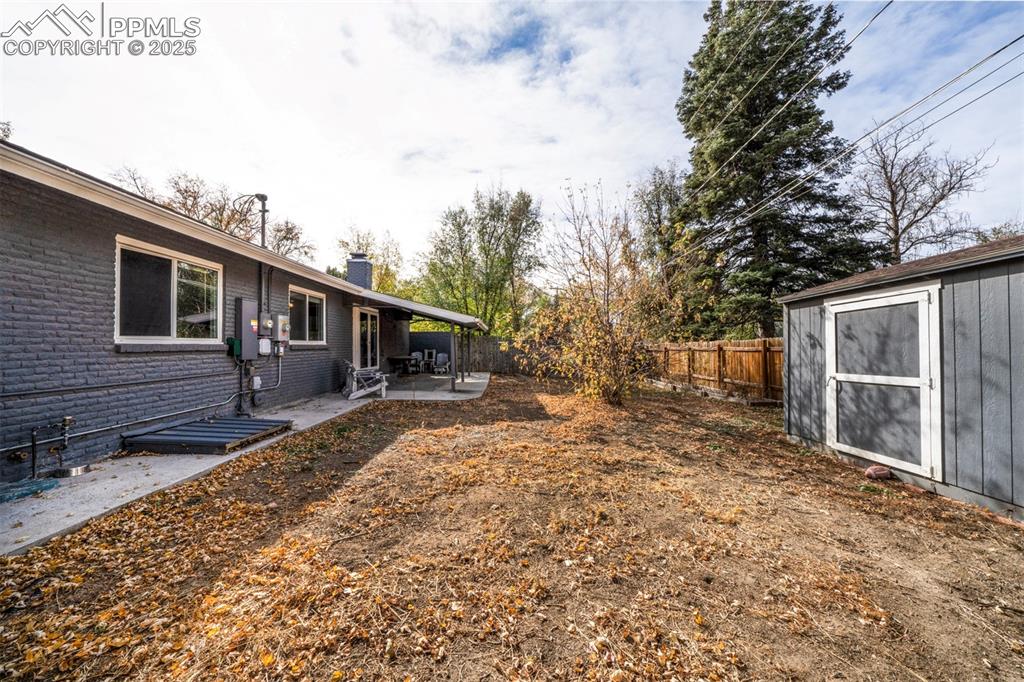Image 40 of 43: Fenced backyard with a covered patio area and a 2 storage units