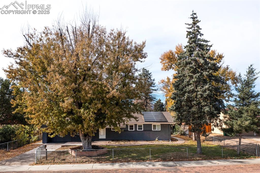 Image 6 of 43: View of front of house with a fenced front yard, brick siding, roof mounted
