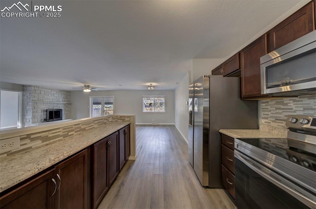 Image 9 of 43: Kitchen with dark brown cabinets, stainless steel appliances, decorative ba