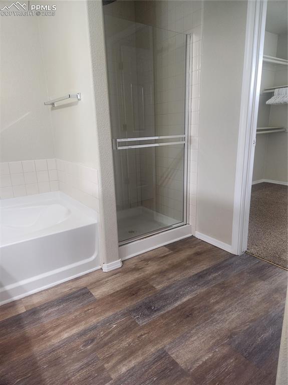 Image 19 of 24: Bathroom featuring a garden tub, a stall shower, dark wood-style floors, an