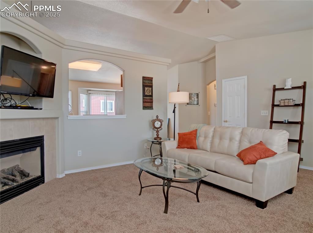 Image 3 of 24: Carpeted living room with vaulted ceiling, a fireplace, and ceiling fan