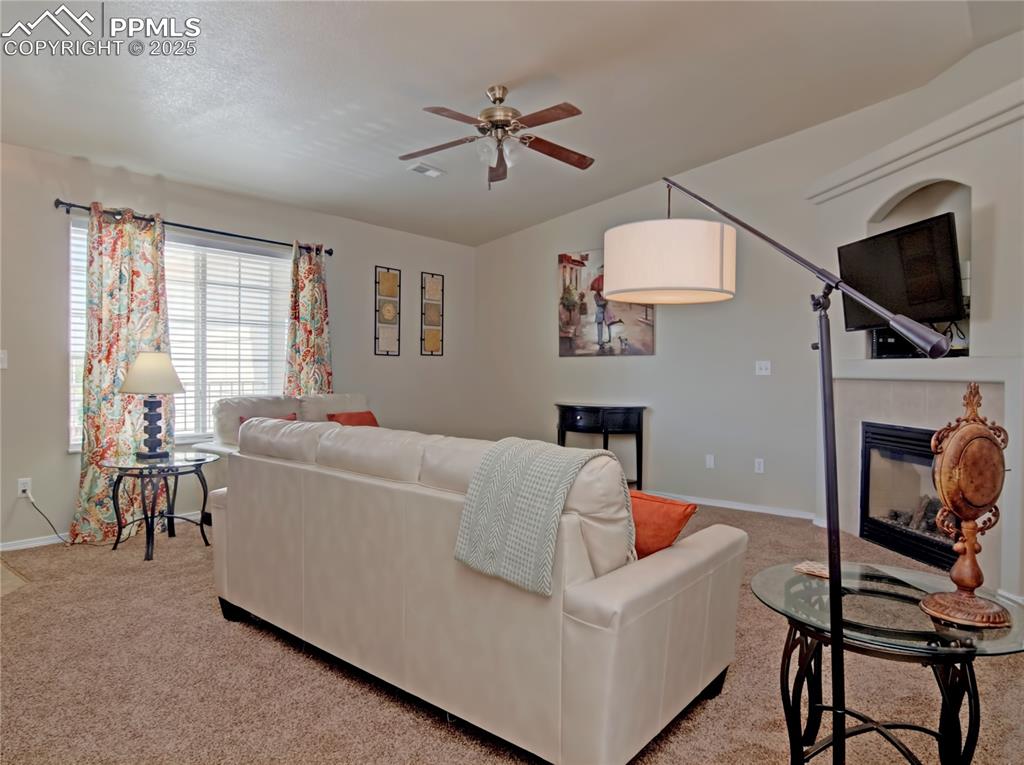 Image 5 of 24: Living room with light colored carpet, a tile fireplace, and ceiling fan