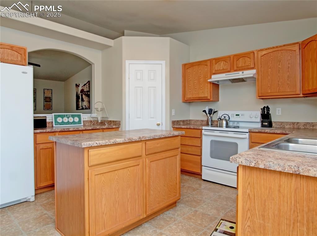 Image 8 of 24: Kitchen with white appliances, a kitchen island, light countertops, under c