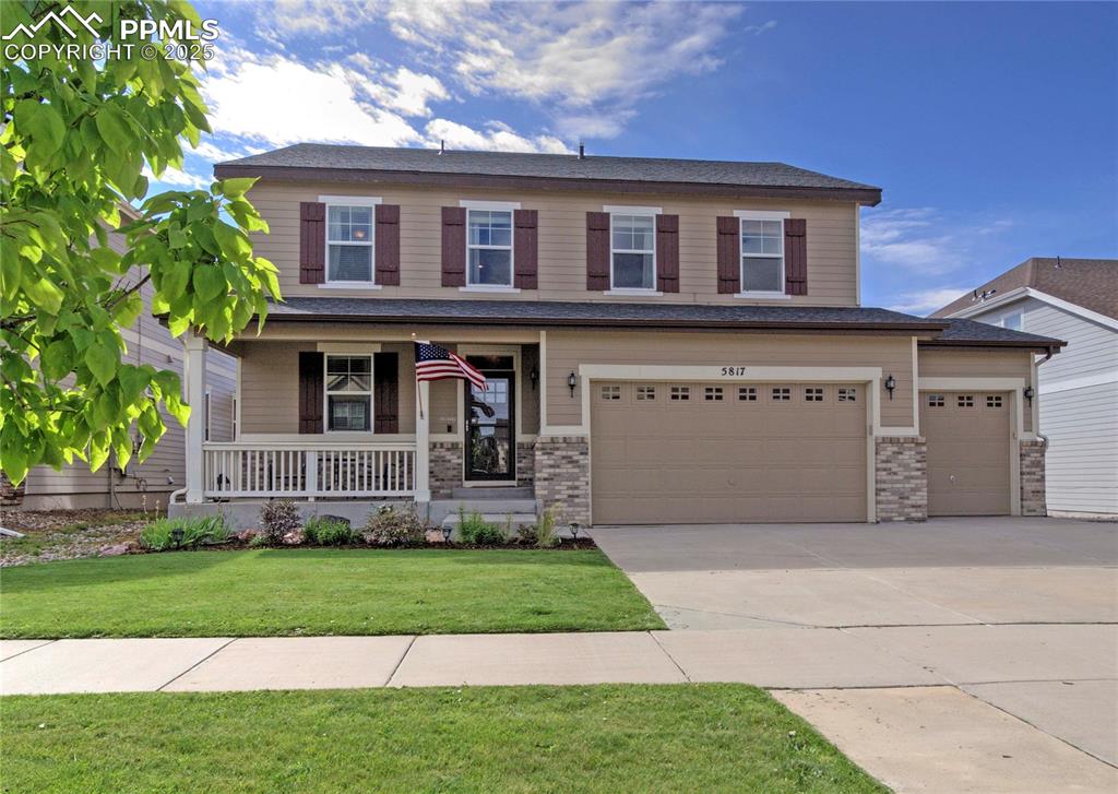 Caption: View of front of house with covered porch, a front lawn, concrete driveway, a garage, and brick sidi