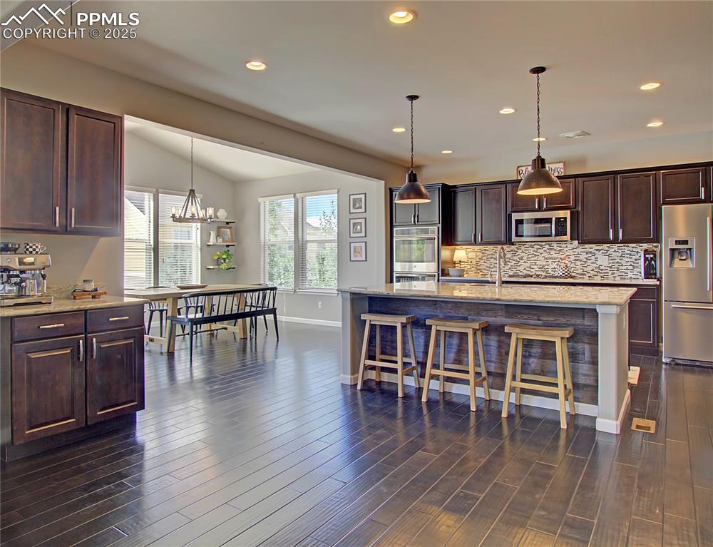 Image 12 of 44: Kitchen featuring dark brown cabinets, stainless steel appliances, light st
