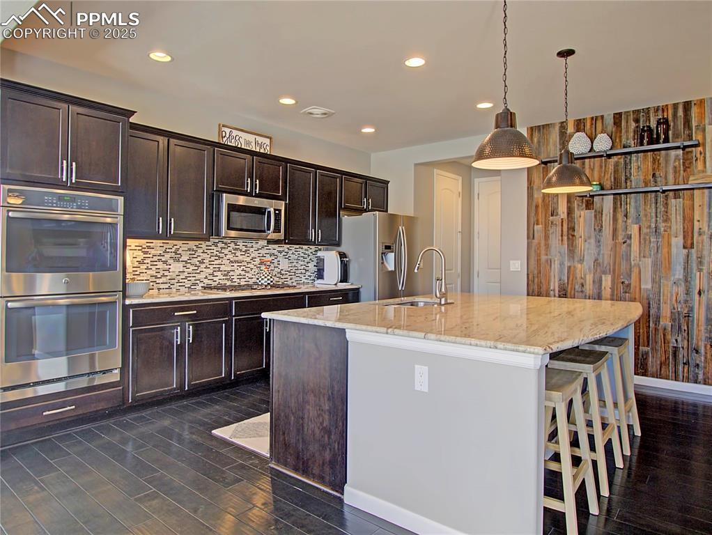Image 13 of 44: Kitchen with stainless steel appliances, featuring double ovens, dark brown