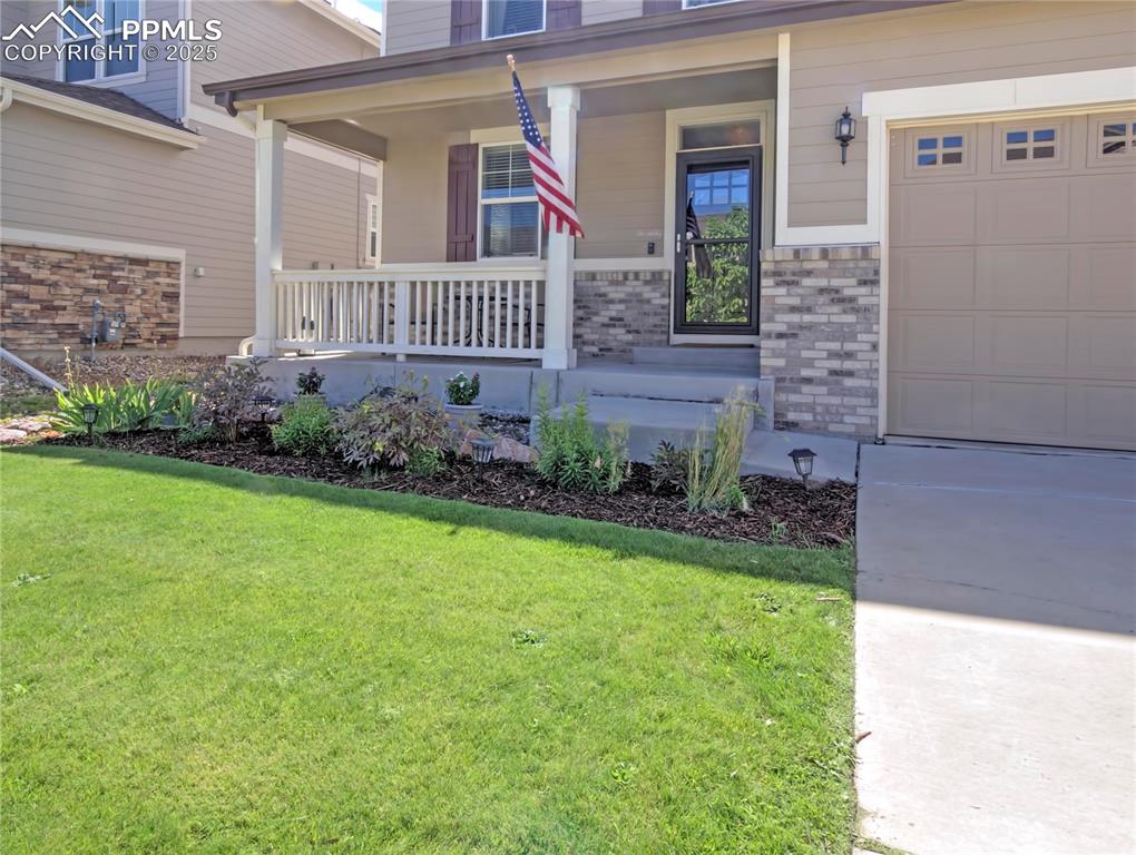Image 2 of 44: Doorway to property with covered porch and a yard