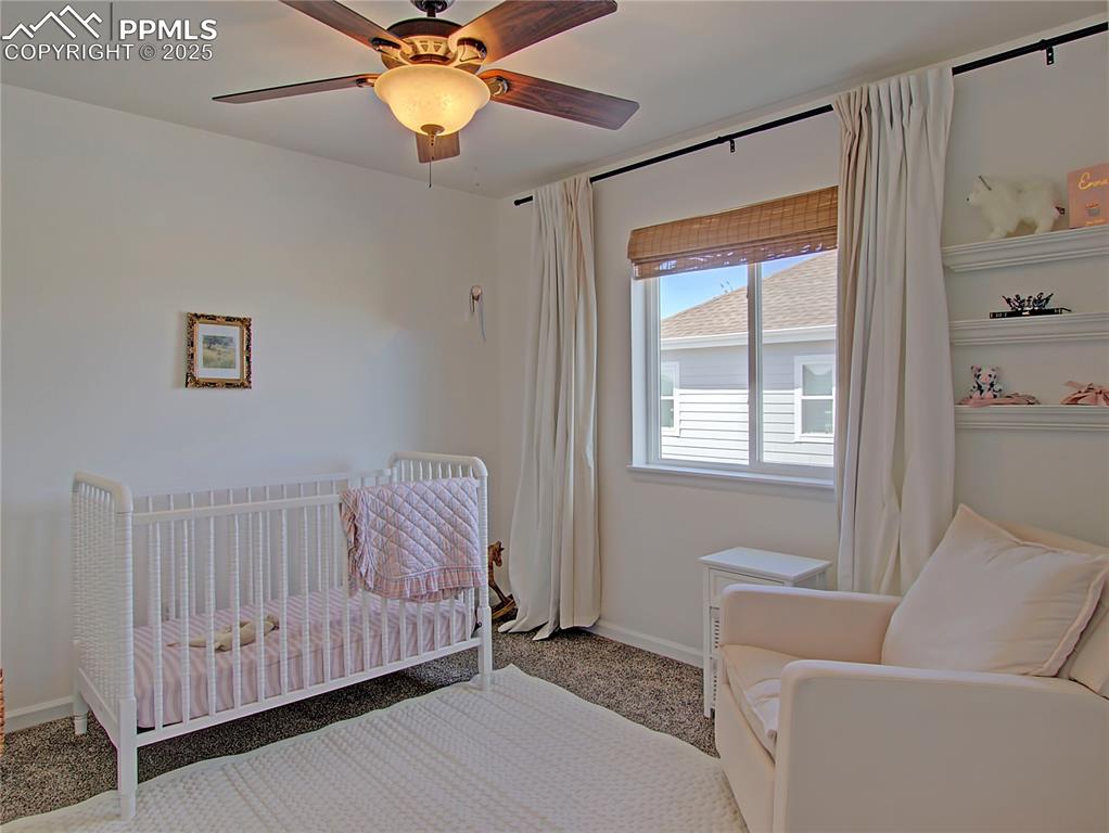 Image 23 of 44: Carpeted bedroom featuring a crib and a ceiling fan