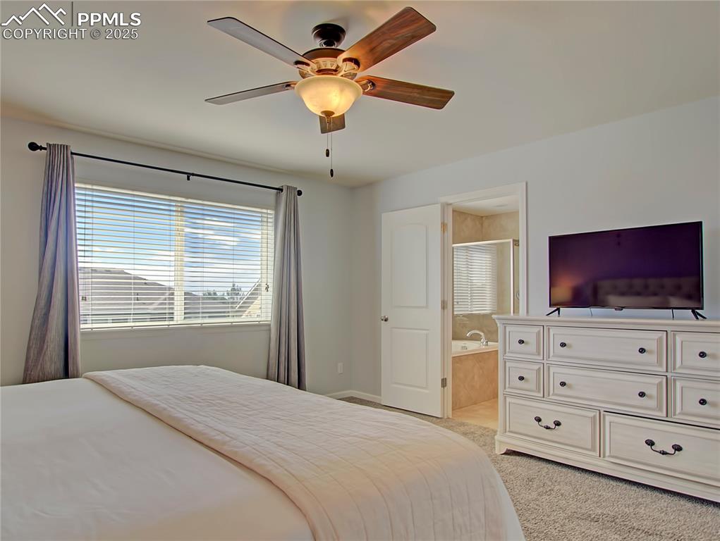 Image 26 of 44: Bedroom featuring a ceiling fan, light carpet, and connected bathroom