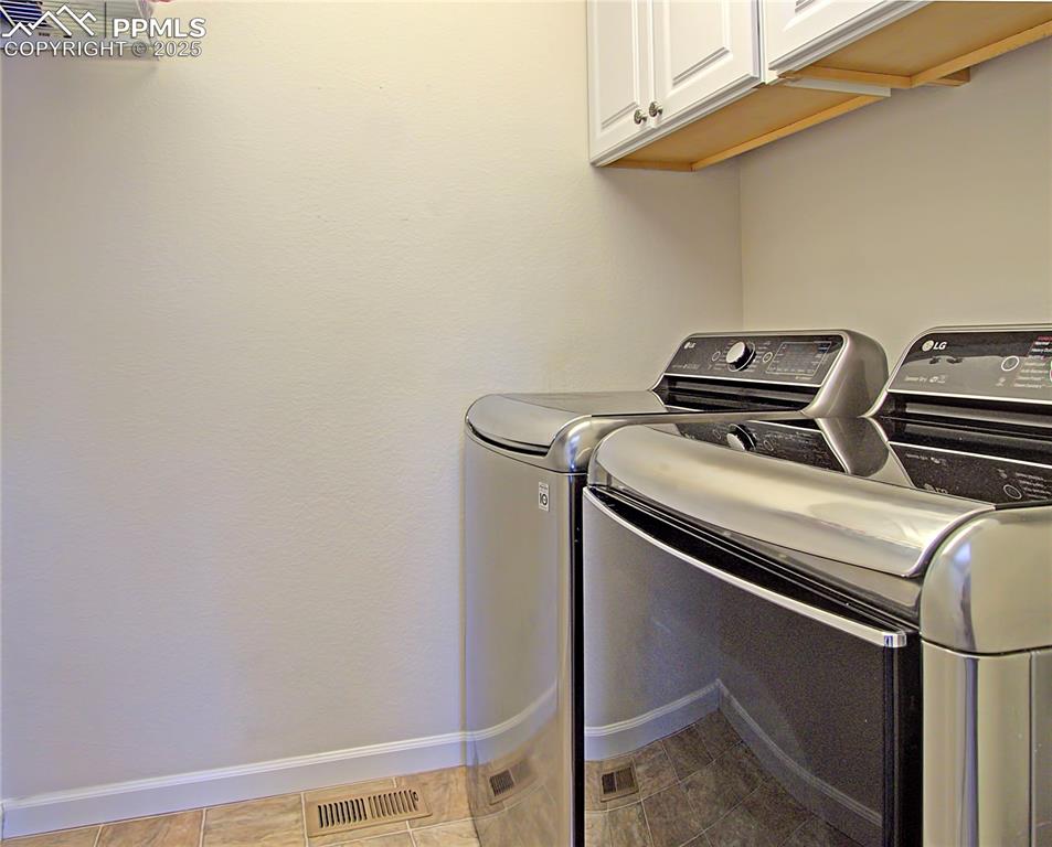 Image 28 of 44: Laundry area featuring cabinet space and washing machine and clothes dryer