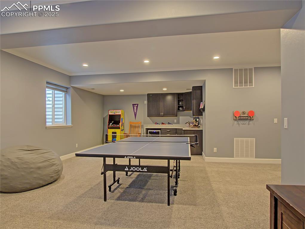Image 32 of 44: Recreation room with light carpet, recessed lighting, and ornamental moldin