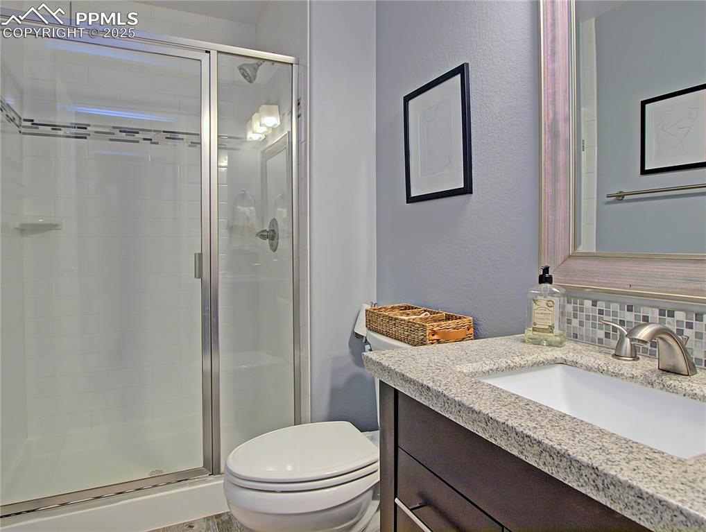 Image 33 of 44: Bathroom with vanity, a shower stall, backsplash, and a textured wall