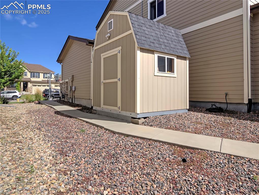Image 38 of 44: View of property exterior with a shingled roof and a storage shed