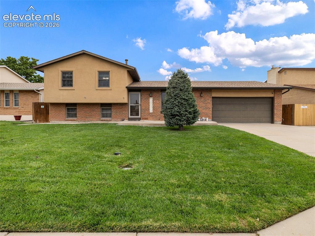 Image 1 of 34: Brick and stucco exterior, attached garage, concrete driveway, front lawn,