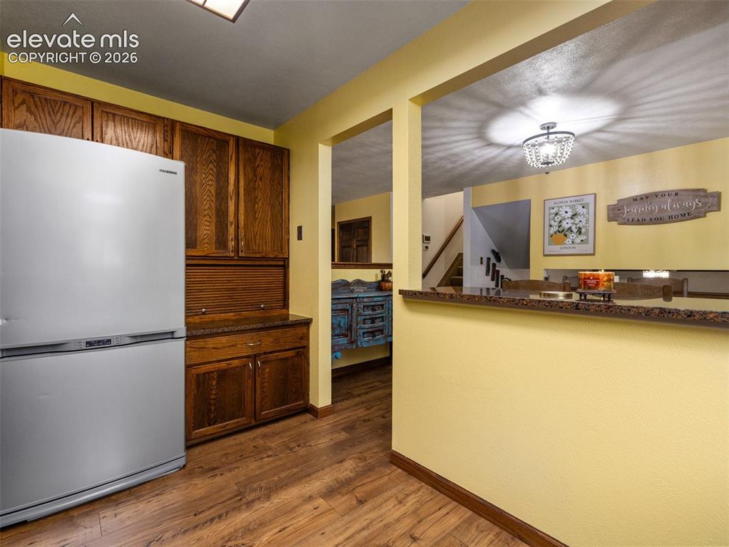 Image 10 of 34: Wood-finish flooring with built-in wood cabinetry, a stainless steel refrig