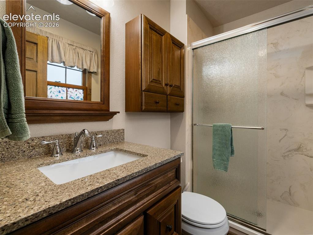 Image 17 of 34: Wood-finish vanity with an integrated rectangular sink, granite-style count