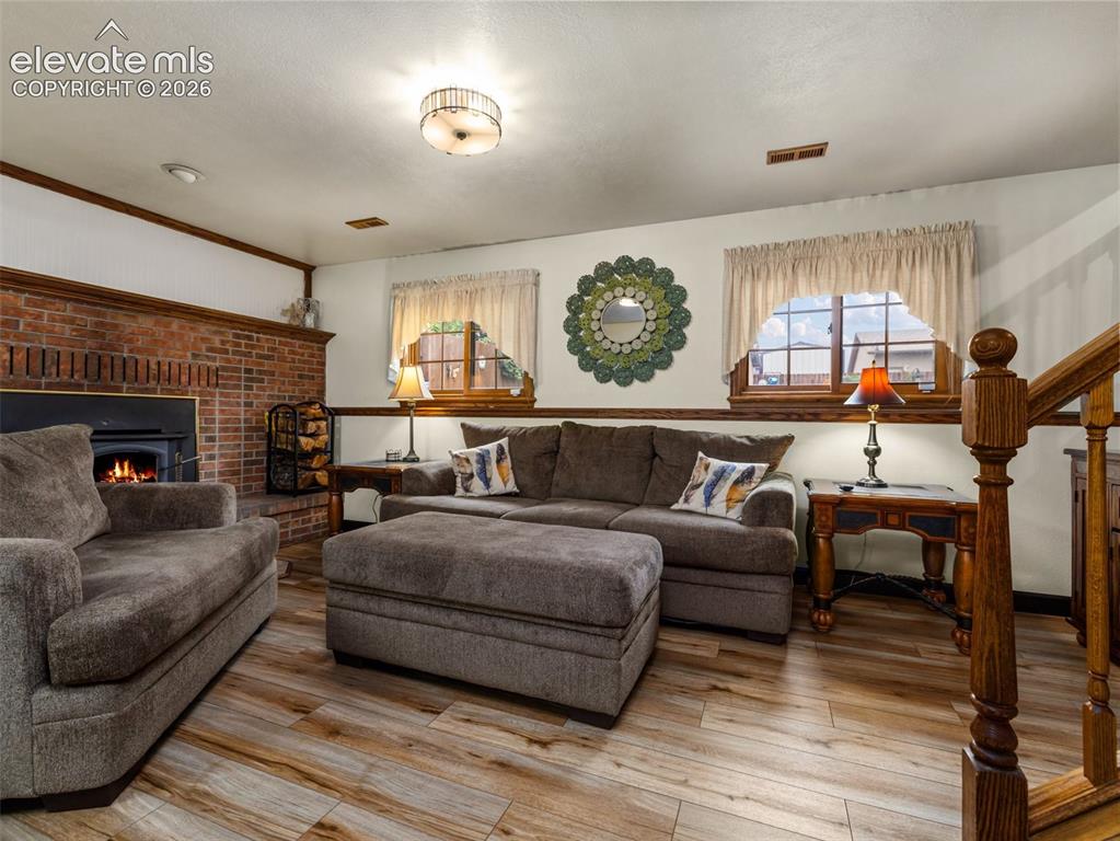 Image 19 of 34: Brick fireplace with wood-burning stove, wood-finish flooring, and wood-tri