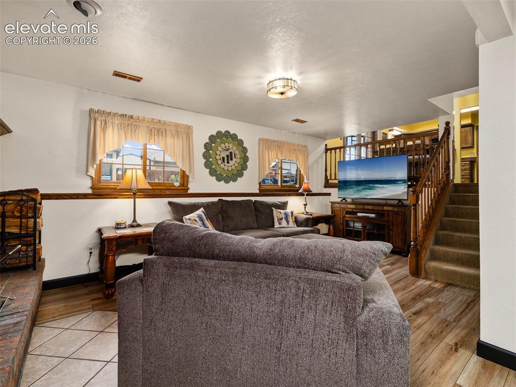 Image 22 of 34: Wood-finish flooring, tiled fireplace hearth, and a wood staircase with car