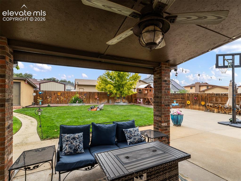 Image 24 of 34: Covered patio with brick columns, ceiling fan, and recessed lighting