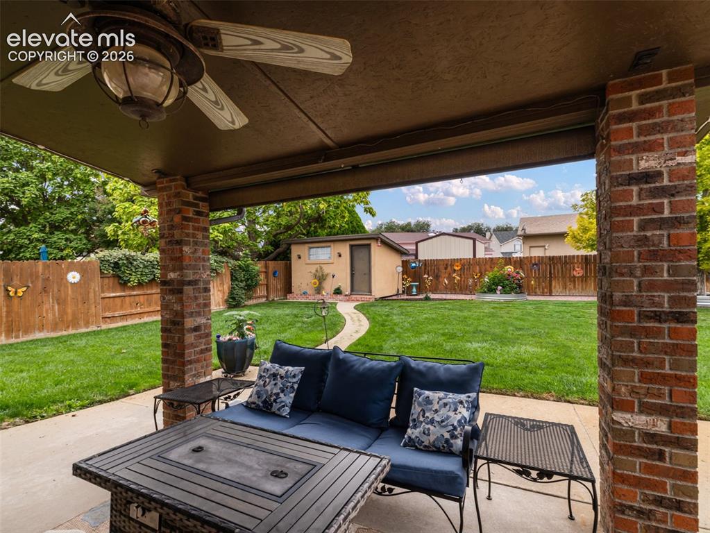 Image 25 of 34: Covered patio with a ceiling fan and brick pillars