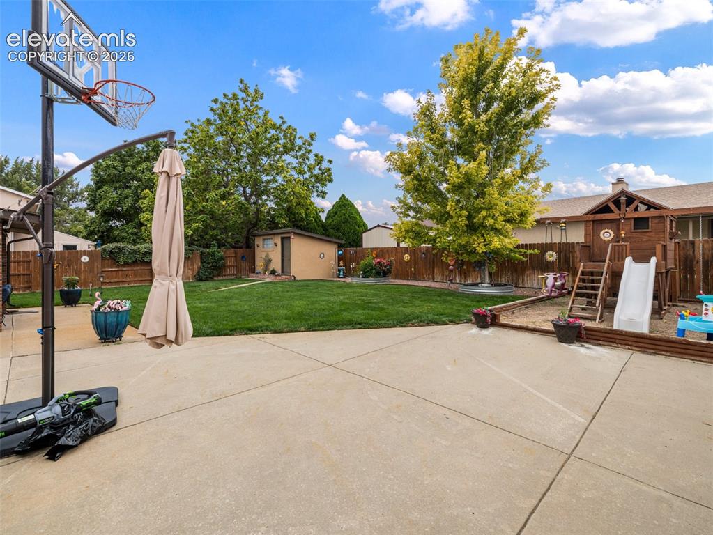 Image 26 of 34: Expansive concrete patio leading to a generous lawn area, featuring a wood