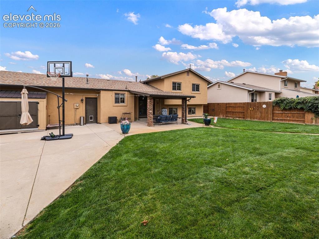 Image 27 of 34: Expansive green lawn, concrete patio, covered outdoor living space, stucco