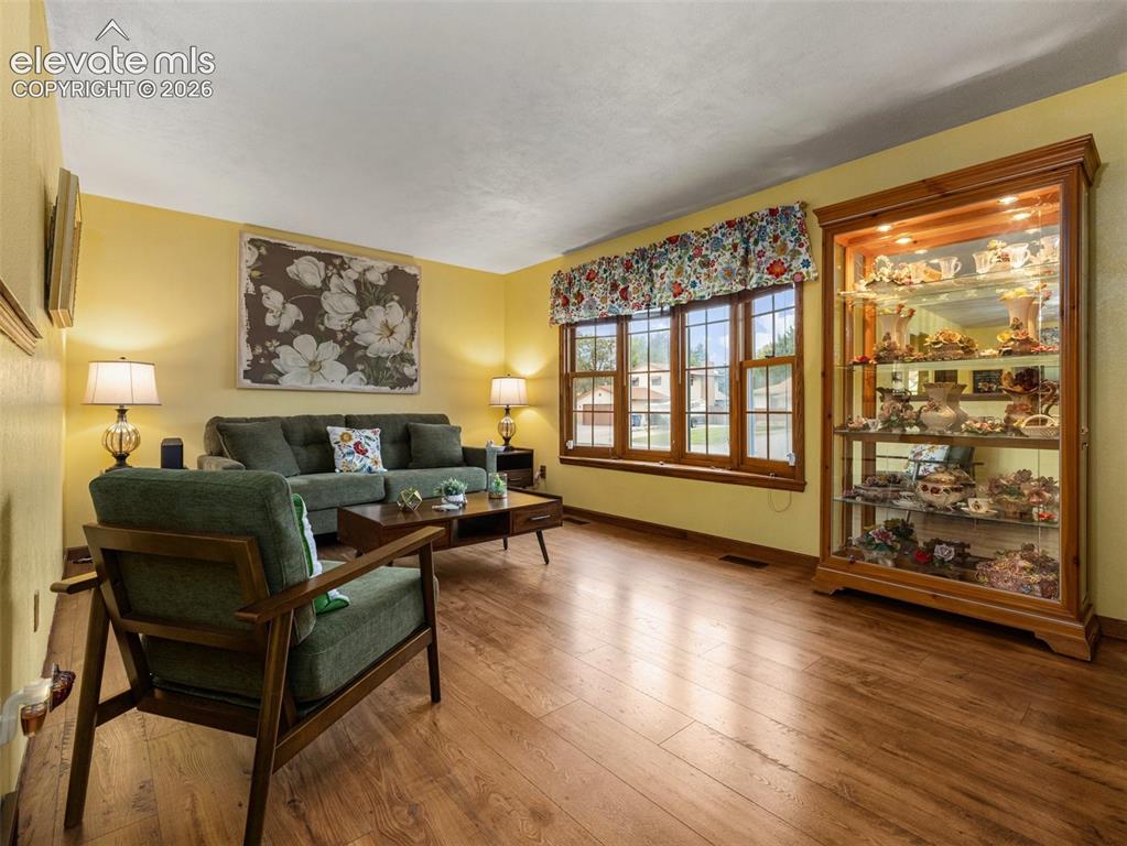 Image 3 of 34: Expansive living area featuring warm wood-finish flooring, a large multi-pa