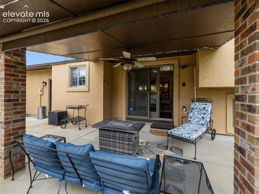 Image 31 of 34: Covered patio with a ceiling fan, concrete flooring, brick columns, and a s