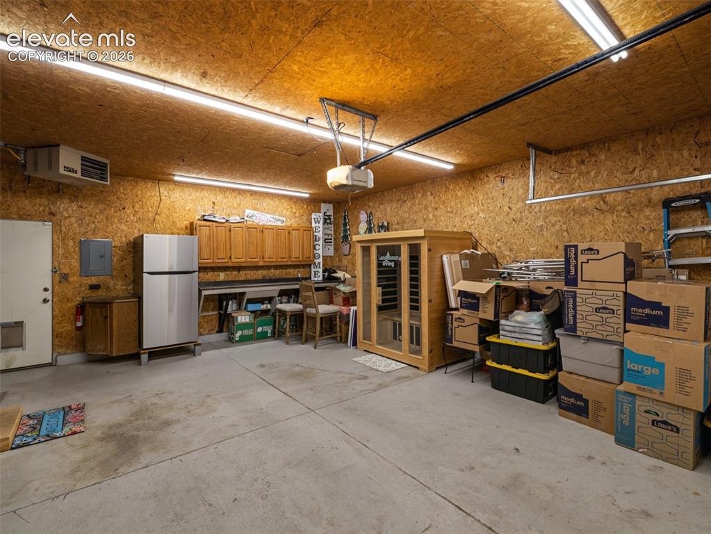 Image 32 of 34: Concrete flooring, wood panel walls, overhead fluorescent lighting, built-i