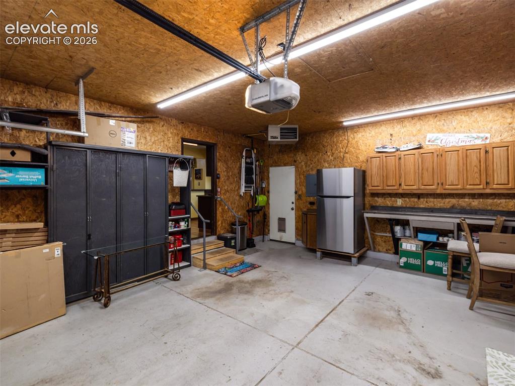 Image 33 of 34: Concrete flooring with overhead fluorescent lighting, wood-paneled walls, a