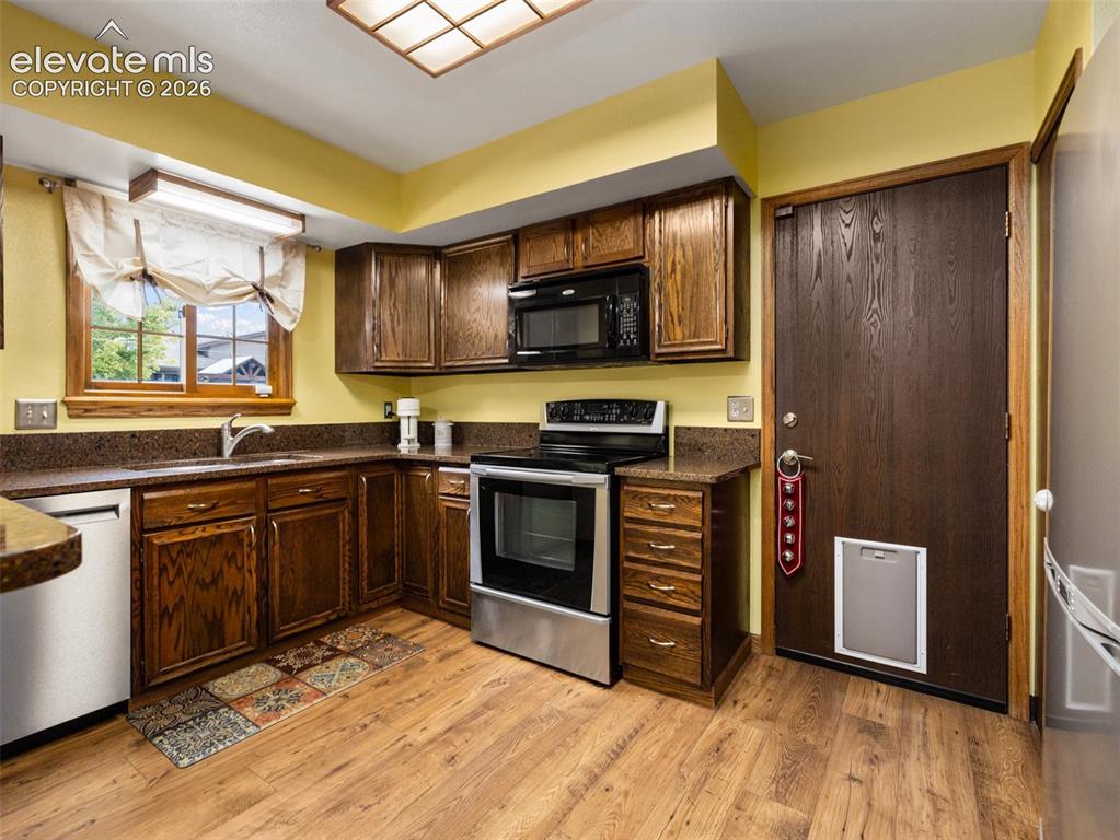 Image 8 of 34: Wood-finish flooring, dark wood cabinetry, stainless steel appliances, dark