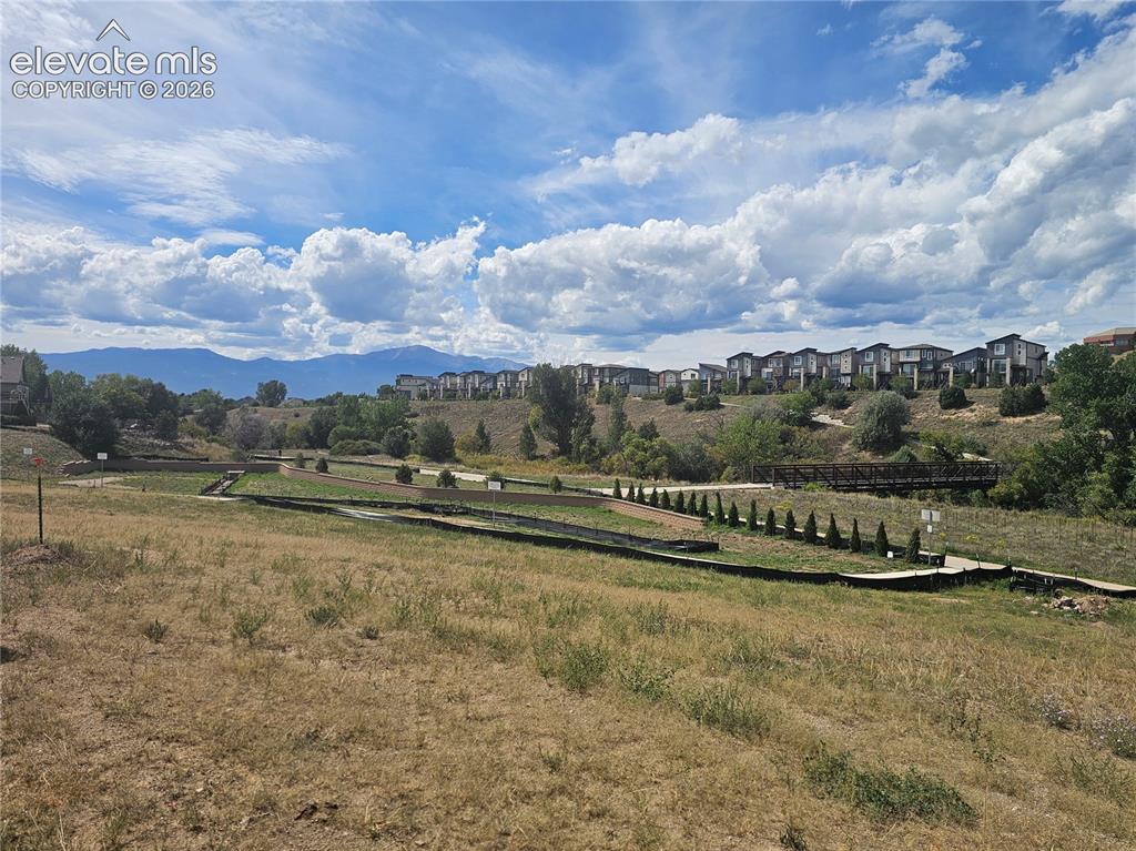 Image 7 of 7: Expansive open space with a wooden footbridge and distant mountain range