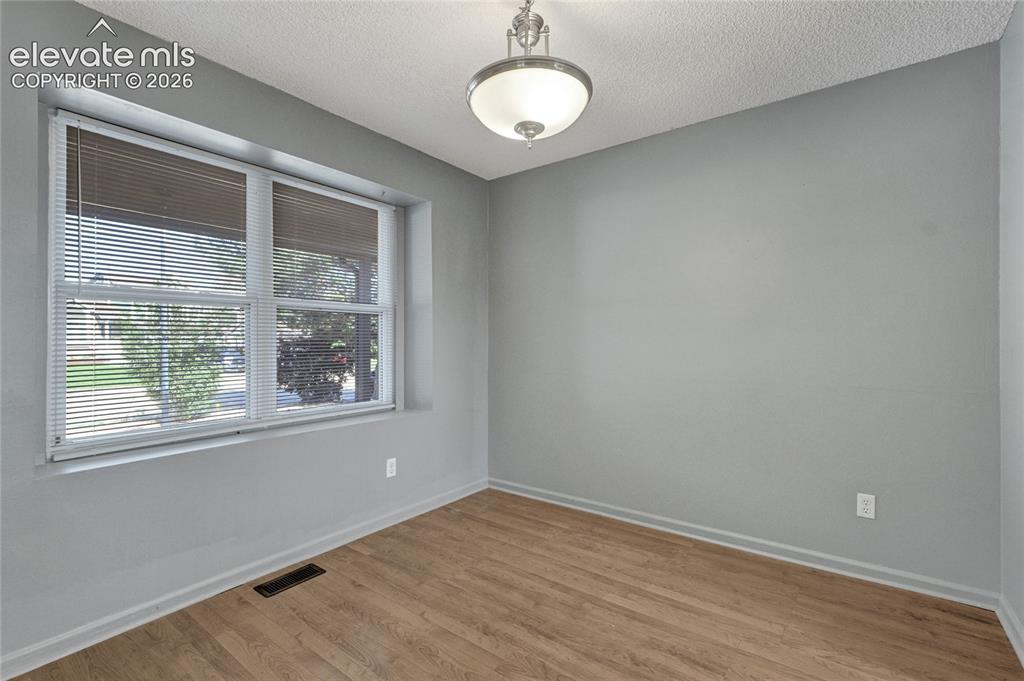 Image 5 of 23: Room featuring light gray walls, wood-finish flooring, and a large window w