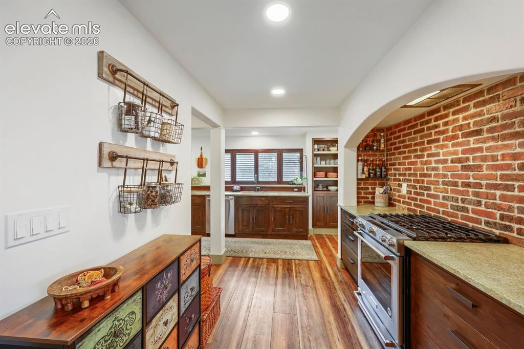 Image 12 of 30: Exposed brick wall detail, hardwood flooring, recessed lighting, built-in c