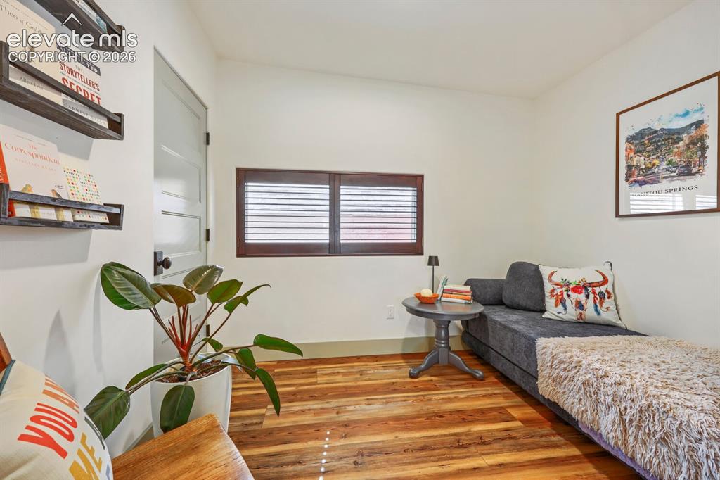 Image 16 of 30: Wood-finish flooring, white walls, and a window with wood shutters