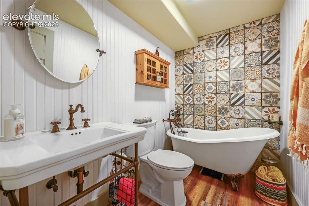 Image 17 of 30: White beadboard paneling, patterned accent wall tile, clawfoot bathtub, ped